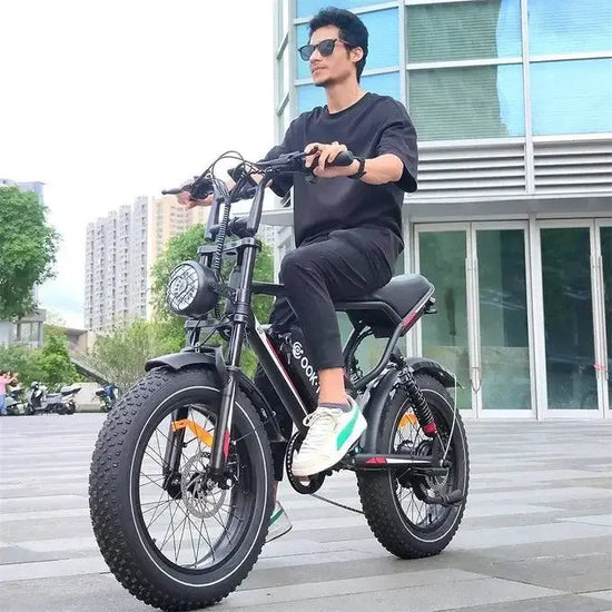 Revolt RV400 Electric Bike being ridden in urban setting, featuring fat tires and sleek design.